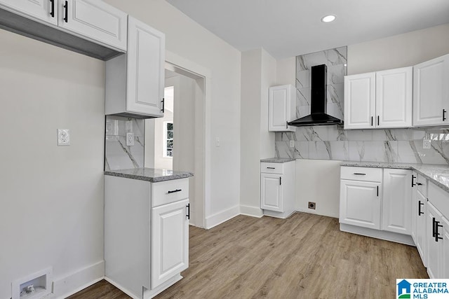 kitchen featuring light hardwood / wood-style floors, wall chimney exhaust hood, white cabinets, and light stone countertops