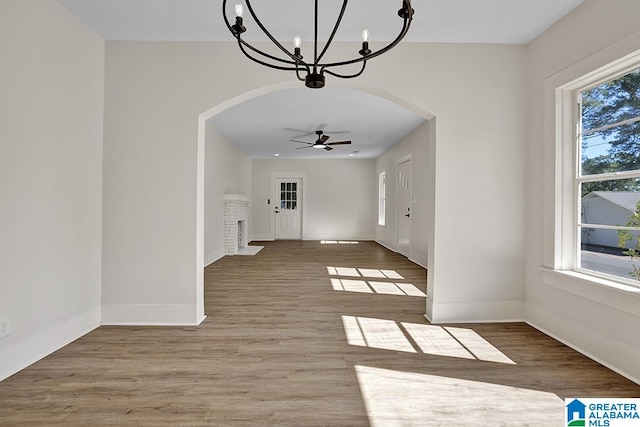 unfurnished dining area with wood-type flooring and ceiling fan with notable chandelier