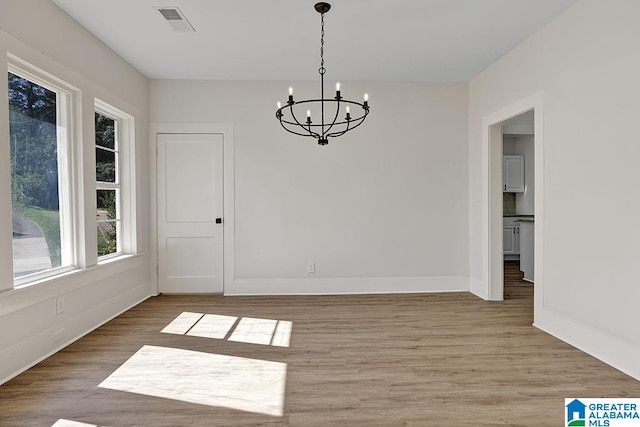 unfurnished dining area with a chandelier and hardwood / wood-style floors