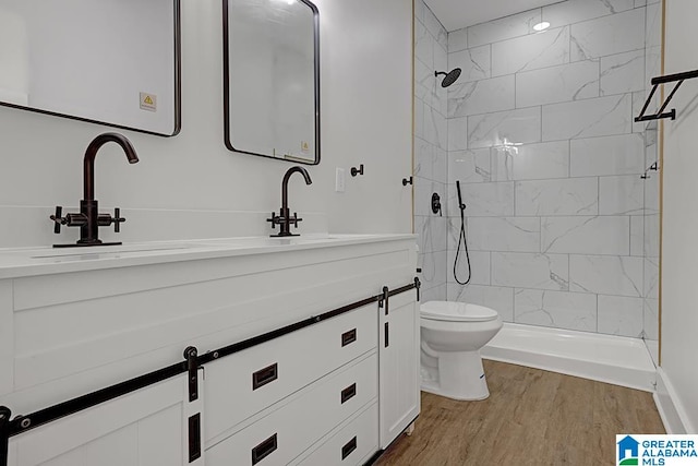 bathroom featuring vanity, a tile shower, hardwood / wood-style flooring, and toilet