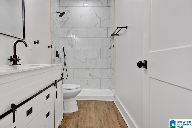 bathroom with vanity, toilet, tiled shower, and hardwood / wood-style floors