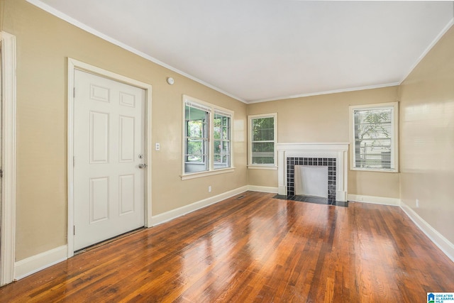 unfurnished living room featuring ornamental molding, dark wood-type flooring, a tile fireplace, and plenty of natural light