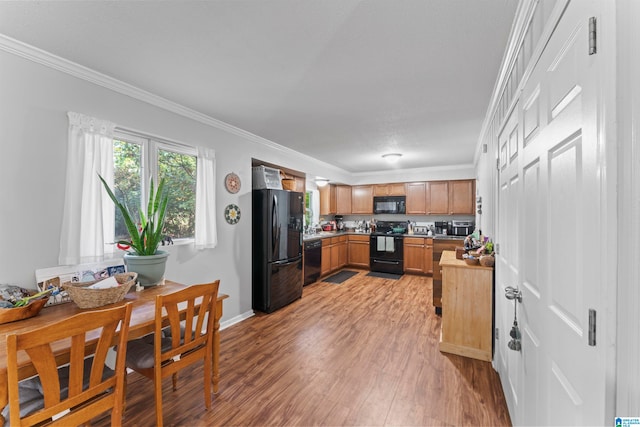 kitchen featuring crown molding, black appliances, and light wood-type flooring