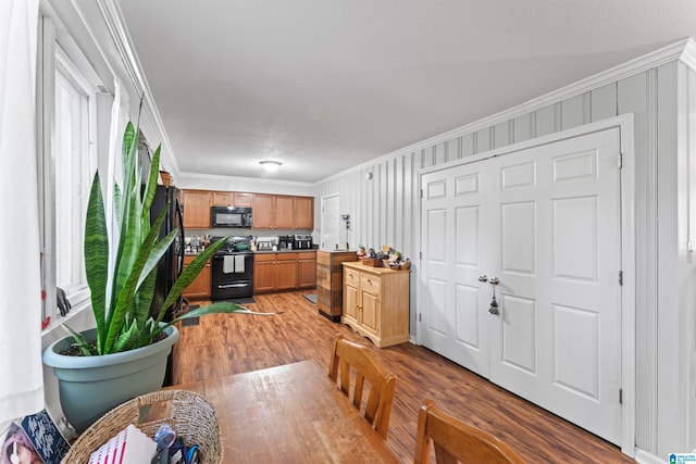 kitchen with ornamental molding, black appliances, and hardwood / wood-style flooring