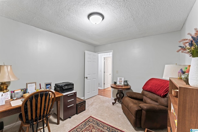 carpeted home office featuring a textured ceiling