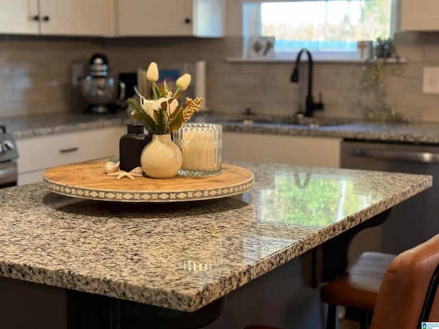 kitchen featuring light stone countertops, sink, white cabinets, and backsplash