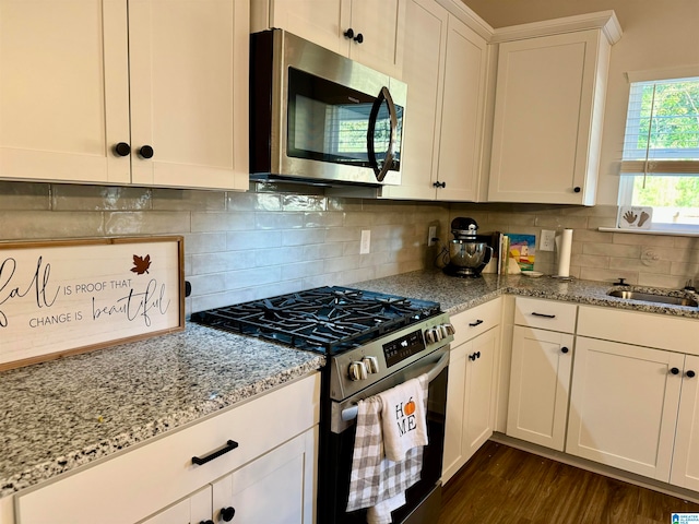 kitchen featuring dark wood-type flooring, appliances with stainless steel finishes, decorative backsplash, and white cabinets