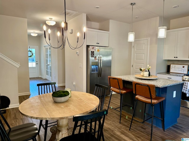 kitchen featuring dark wood-type flooring, stainless steel appliances, a breakfast bar, a center island, and white cabinetry