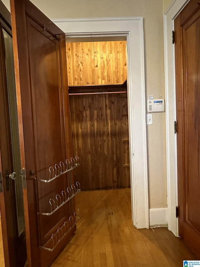 hall with hardwood / wood-style floors and wooden walls