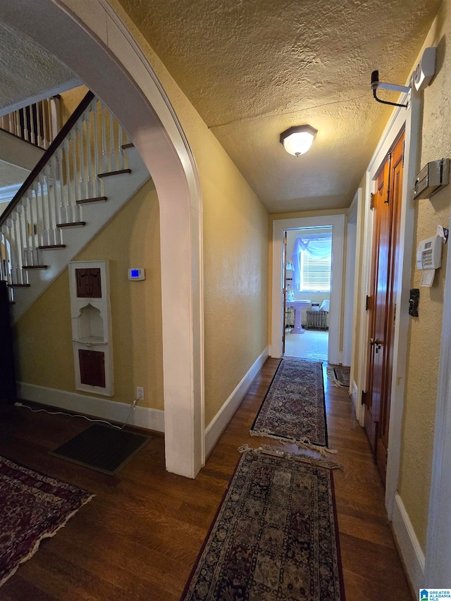 hallway featuring a textured ceiling and dark wood-type flooring