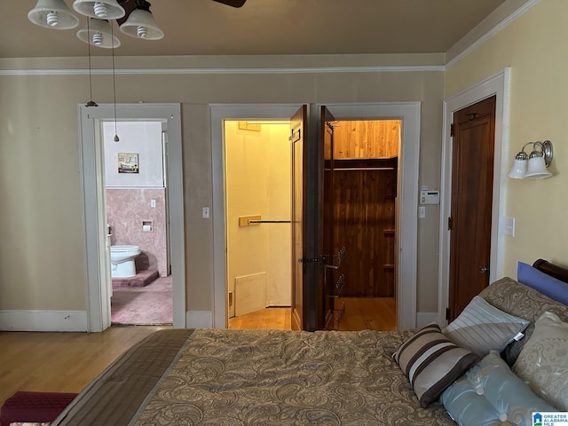 bedroom with crown molding, hardwood / wood-style flooring, a closet, and ensuite bath