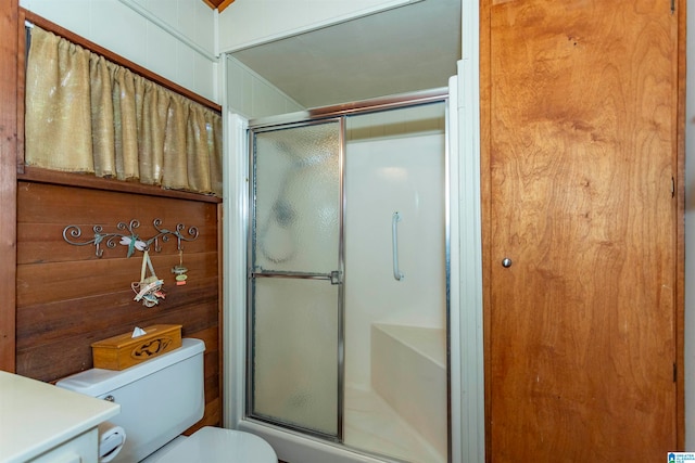 bathroom featuring toilet, vanity, and a shower with door