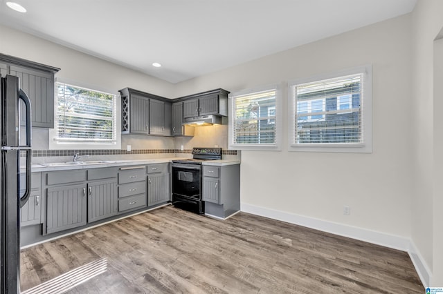 kitchen with black appliances, sink, hardwood / wood-style floors, and gray cabinets