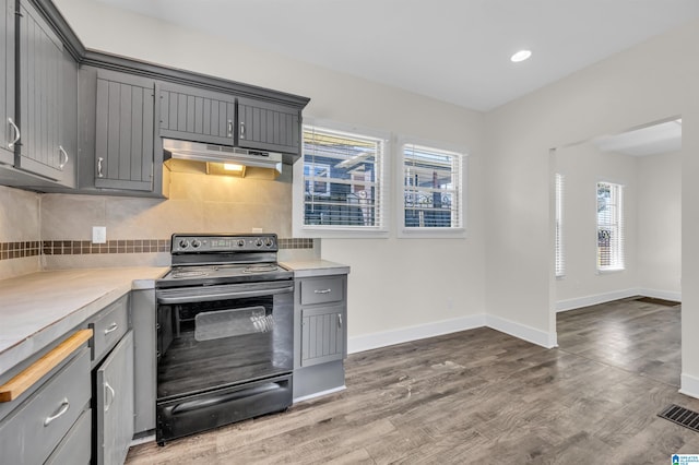 kitchen featuring black / electric stove, decorative backsplash, dark hardwood / wood-style flooring, and gray cabinetry