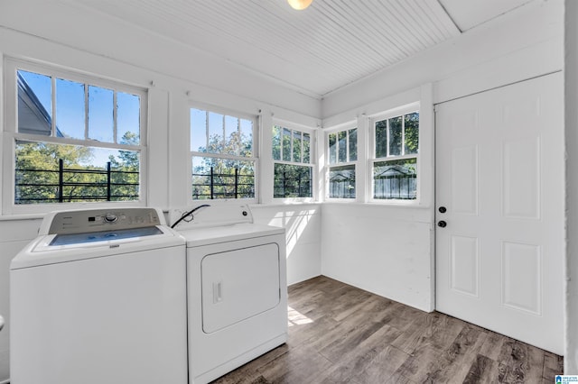 washroom with a wealth of natural light, washing machine and clothes dryer, and wood-type flooring