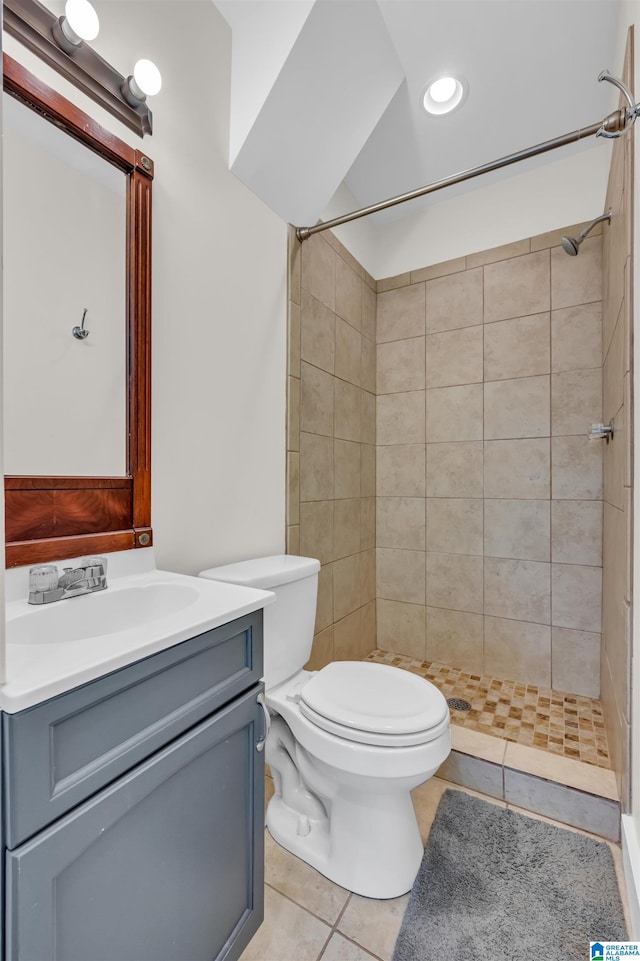 bathroom featuring vanity, toilet, tiled shower, and tile patterned flooring