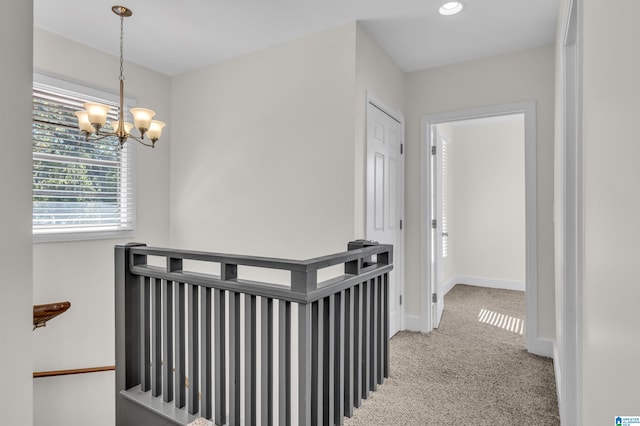 hall featuring carpet floors and an inviting chandelier