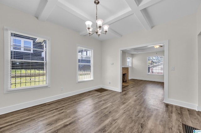 interior space with beam ceiling, a wealth of natural light, a brick fireplace, and hardwood / wood-style floors