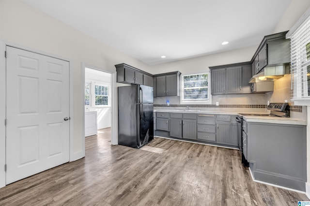 kitchen with electric range oven, gray cabinetry, plenty of natural light, and black fridge