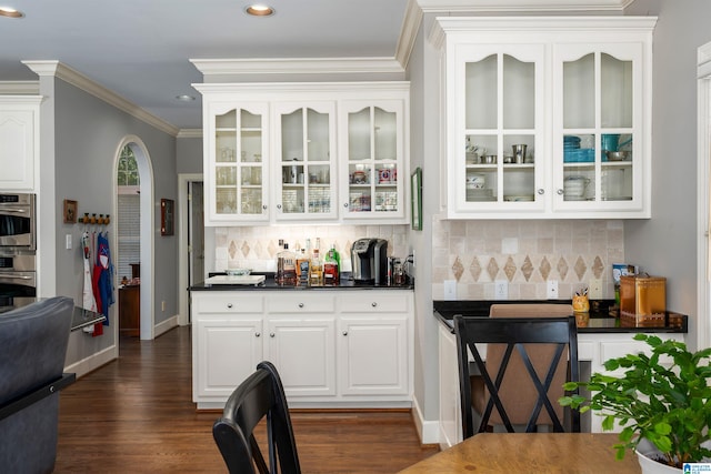 bar with ornamental molding, dark wood-type flooring, white cabinets, and decorative backsplash