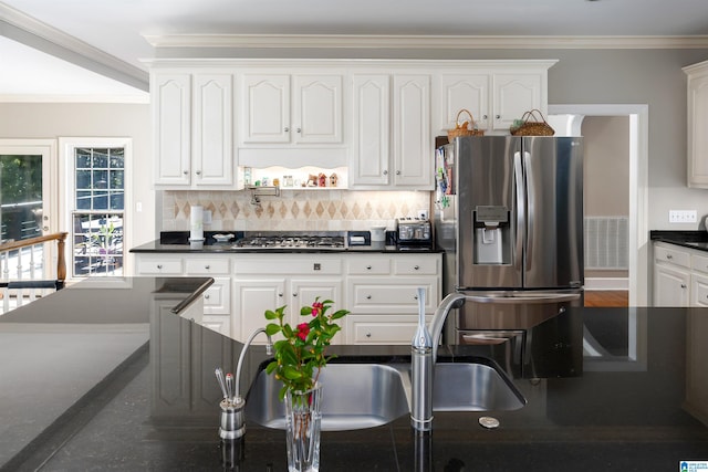 kitchen with ornamental molding, decorative backsplash, appliances with stainless steel finishes, and white cabinets