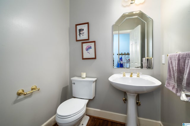 bathroom featuring toilet, wood-type flooring, and sink