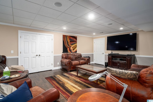 living room with dark wood-type flooring, ornamental molding, and a drop ceiling