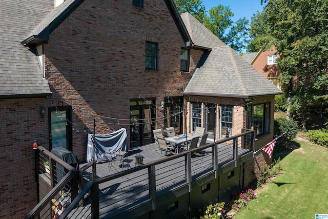 rear view of house featuring a wooden deck and a lawn