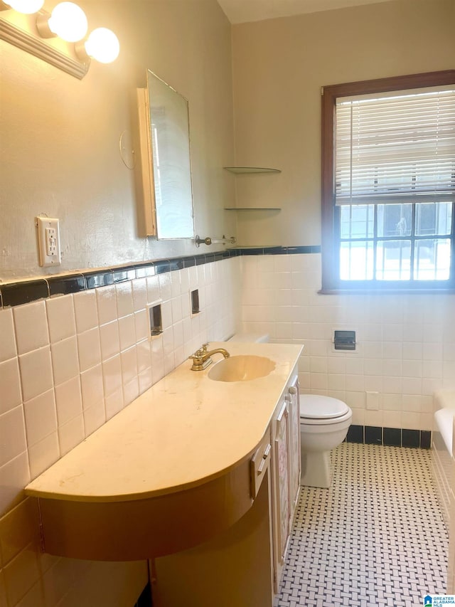 bathroom with toilet, vanity, tile walls, and tile patterned flooring