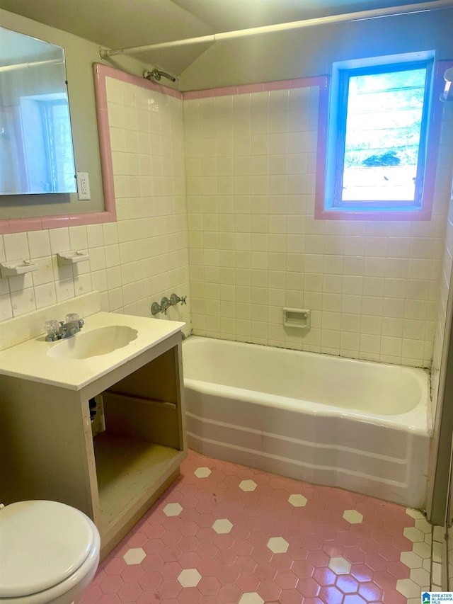 full bathroom with tiled shower / bath, tile walls, toilet, vanity, and tile patterned floors