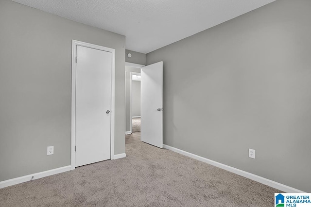 unfurnished bedroom featuring light carpet and a textured ceiling