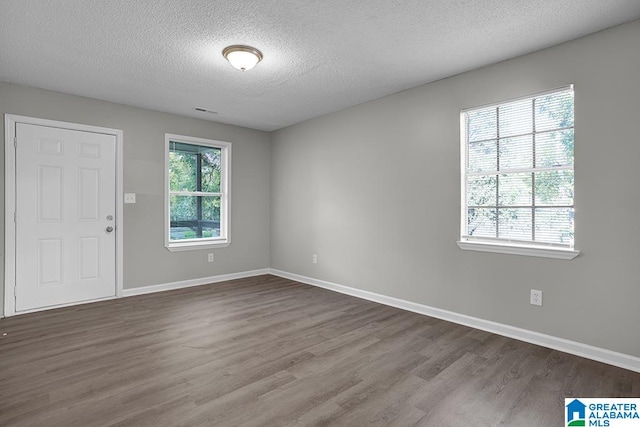 spare room with a textured ceiling and wood-type flooring