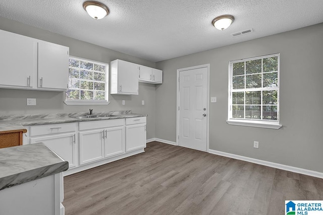 kitchen featuring sink, white cabinetry, a textured ceiling, and light wood-type flooring