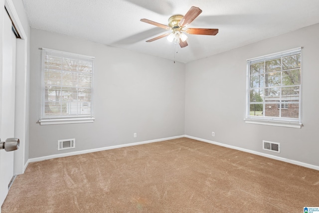 spare room with ceiling fan, light colored carpet, and a textured ceiling