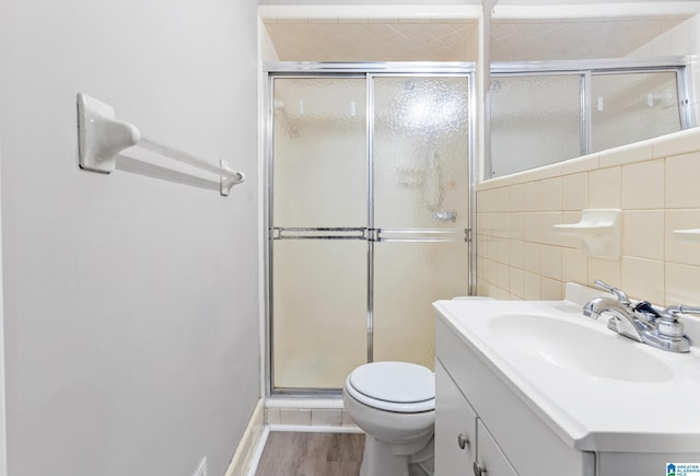 bathroom featuring toilet, hardwood / wood-style floors, a shower with shower door, and vanity