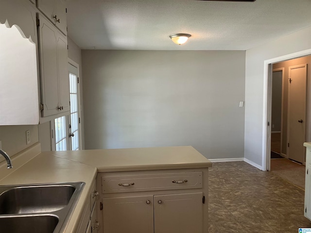 kitchen featuring white cabinets, a textured ceiling, and sink