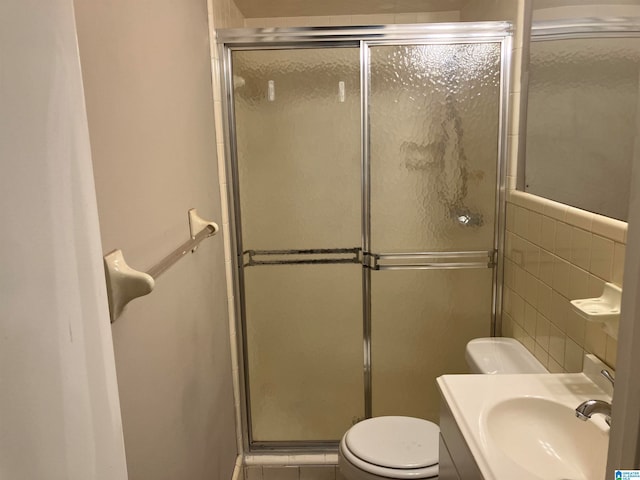 bathroom with tile walls, walk in shower, sink, and toilet