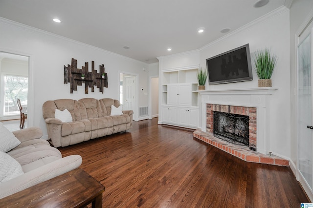 living room with crown molding, a brick fireplace, and dark hardwood / wood-style floors