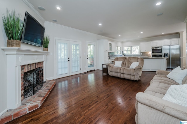 living room featuring crown molding, a fireplace, dark hardwood / wood-style floors, and french doors