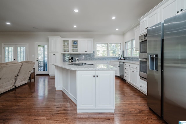 kitchen with appliances with stainless steel finishes, white cabinetry, dark hardwood / wood-style floors, and a kitchen island