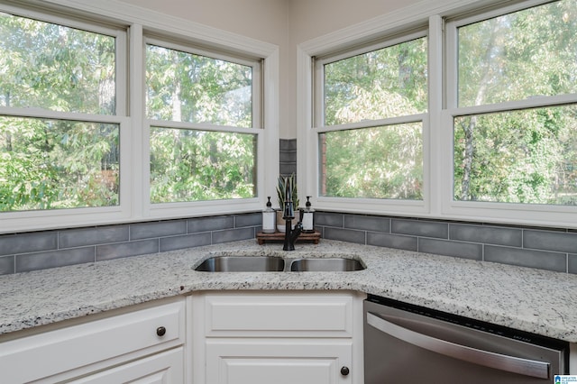 kitchen featuring white cabinetry, a healthy amount of sunlight, light stone countertops, and dishwasher