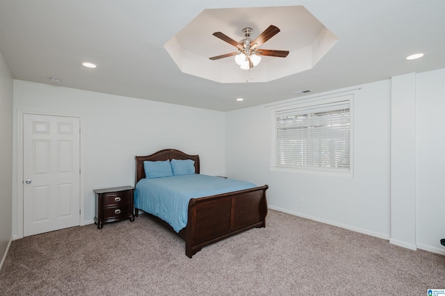 bedroom featuring a raised ceiling, light carpet, and ceiling fan