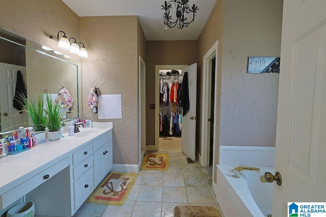 bathroom with an inviting chandelier, vanity, a bath, and tile patterned flooring