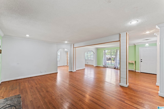 unfurnished living room featuring crown molding, a textured ceiling, and hardwood / wood-style floors