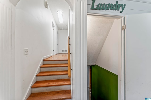 stairs featuring a textured ceiling