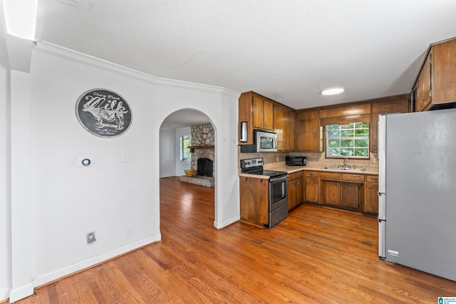 kitchen with appliances with stainless steel finishes, sink, hardwood / wood-style floors, a wealth of natural light, and ornamental molding