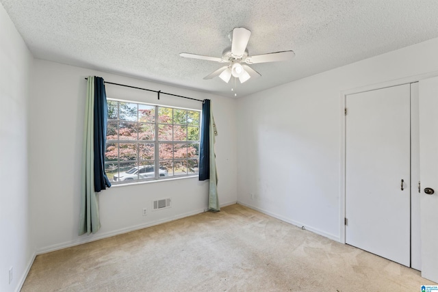 carpeted empty room with a textured ceiling and ceiling fan