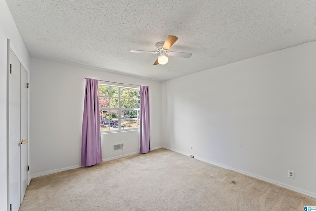 unfurnished room with ceiling fan, light carpet, and a textured ceiling