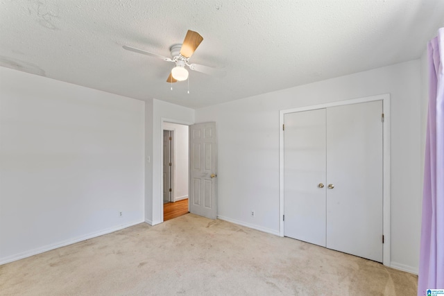 unfurnished bedroom featuring light carpet, a textured ceiling, a closet, and ceiling fan