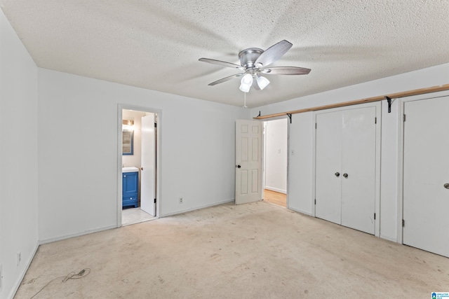 unfurnished bedroom with light carpet, a textured ceiling, ensuite bathroom, and ceiling fan